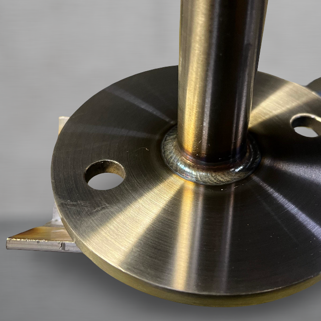 Edelstahl Schweißarbeit für eine Fassadenbegrünung Industriebau Nachhaltig Klimafreundlich Korrosisonsbeständig Nahaufnahme eines metallenen Flansches mit einem vertikalen Rohr und Schweißnaht.